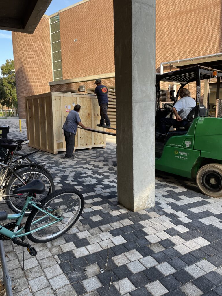 Movers unloading a crated Gen II MBE system outside CREOL